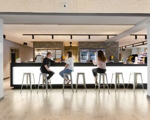 A modern bar area with a counter, stools, and a visible restroom sign. - a&o Frankfurt Galluswarte - Hostel (Frankfurt)