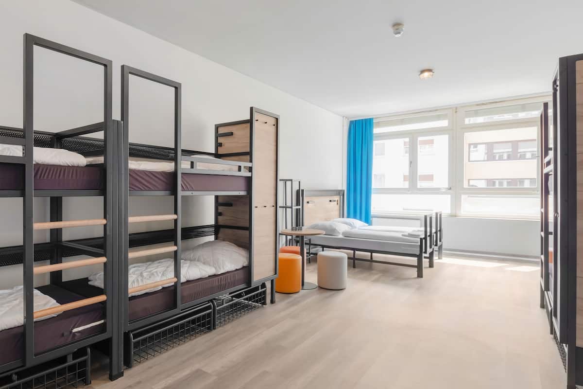 Une chambre de dortoir avec des lits superposés, un bureau, une chaise et une fenêtre avec des rideaux.