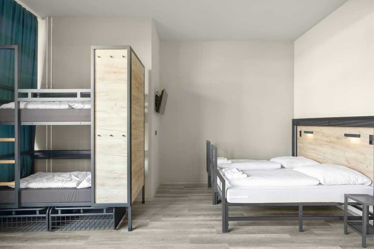 Une chambre avec des lits superposés, un lit simple et une petite table.