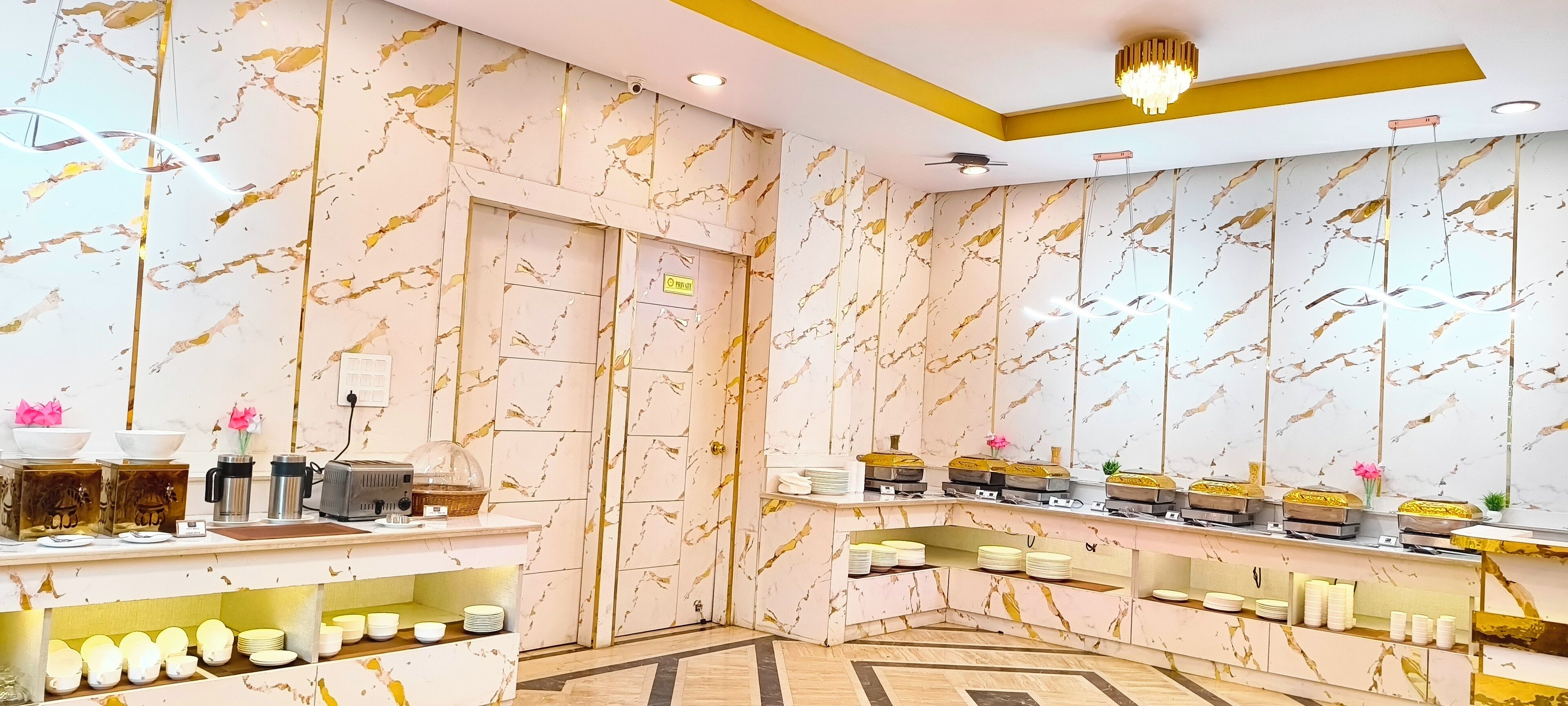 A hotel reception area with marble-patterned walls, a reception desk, and a buffet setup.