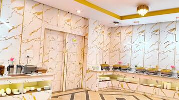 A hotel reception area with marble-patterned walls, a reception desk, and a buffet setup.