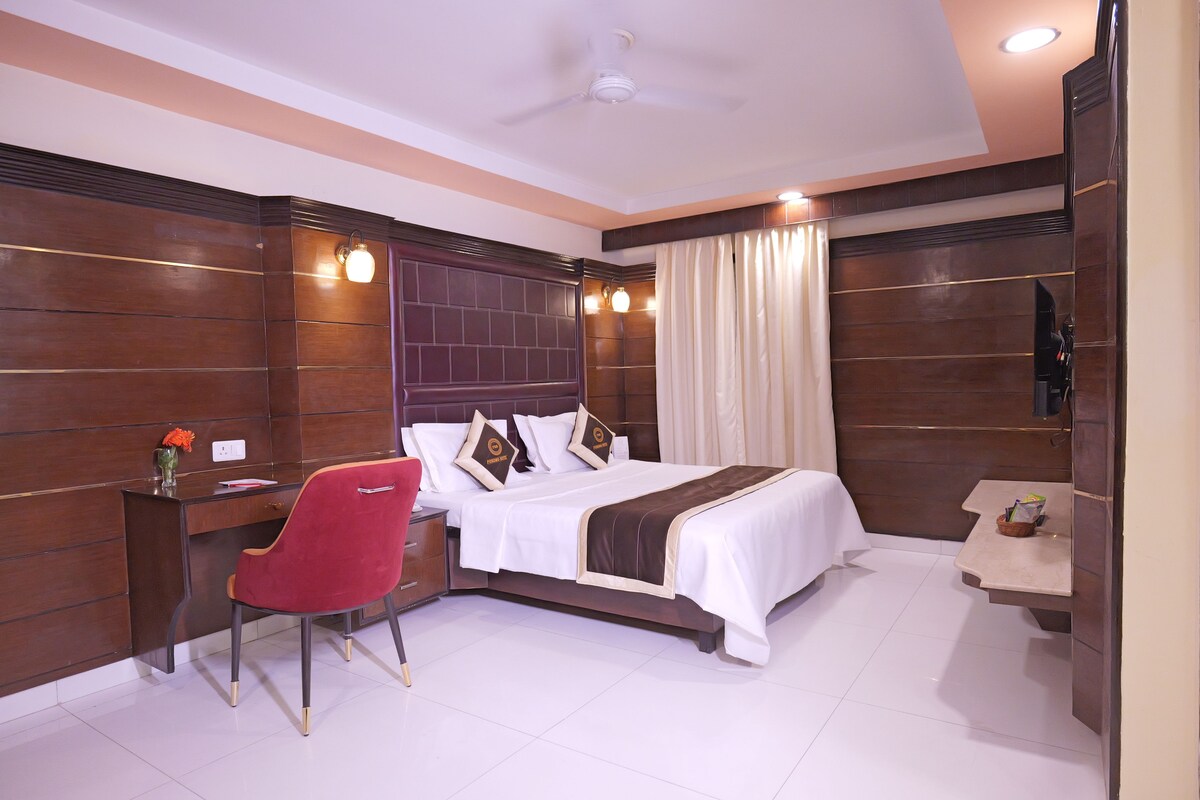 Une chambre d’hôtel avec un lit, un bureau, une chaise et un téléviseur.