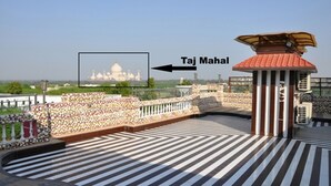 A view of the Taj Mahal from a rooftop terrace with a patterned floor and a small pavilion. - Foxoso Taj View Hotel (Agra)