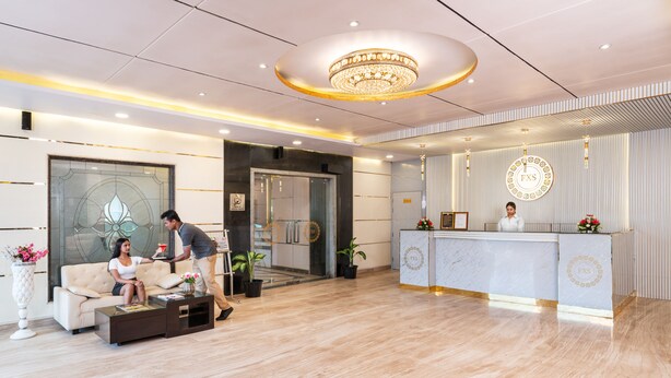 A modern hotel lobby with a reception desk, a seating area with a sofa and coffee table, and a decorative chandelier. - Foxoso Taj View Hotel (Agra)