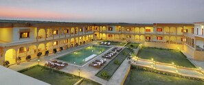 Un patio con piscina, sillas de descanso y un césped bien cuidado.