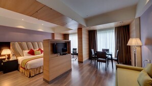 A hotel room with a large bed, a desk, and a dining area. - Hotel Combermere (Shimla)