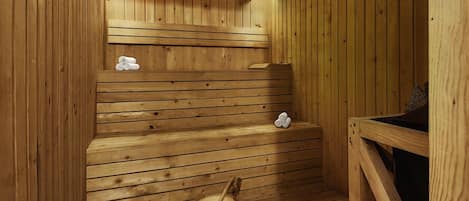 Una sauna de madera con bancos y un balde de madera.