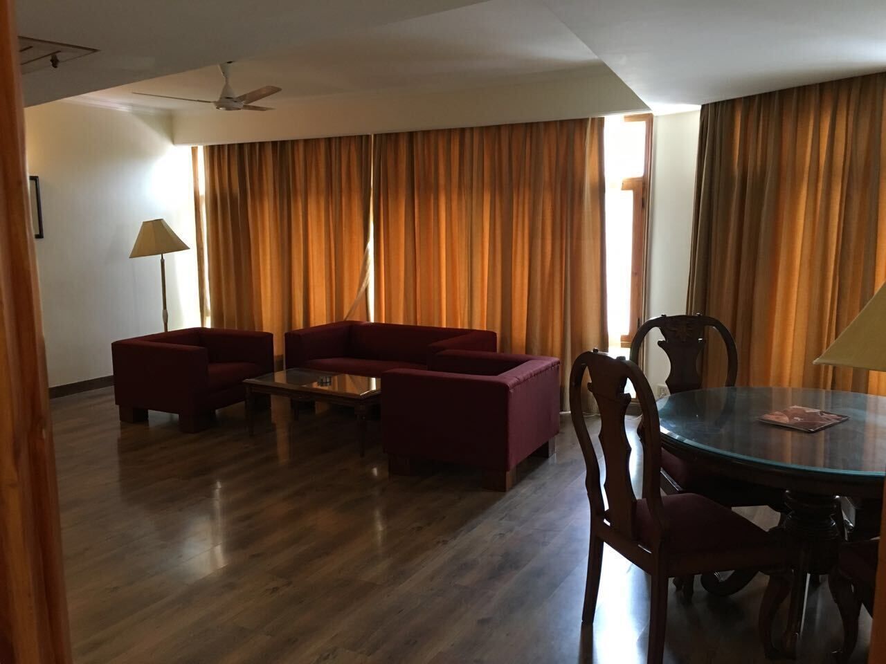 Un salon avec un canapé rouge, une table basse en verre et une table à manger avec des chaises.