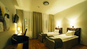Habitación de hotel con dos camas, un escritorio, una silla, un televisor y un cuadro en la pared.