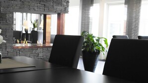 Un comedor moderno con pared de piedra, sillas negras, una mesa y una planta en maceta.