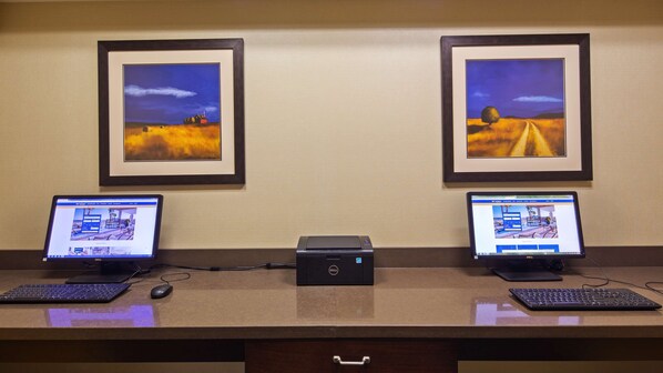 A reception desk with two computers, a printer, and framed artwork on the wall.