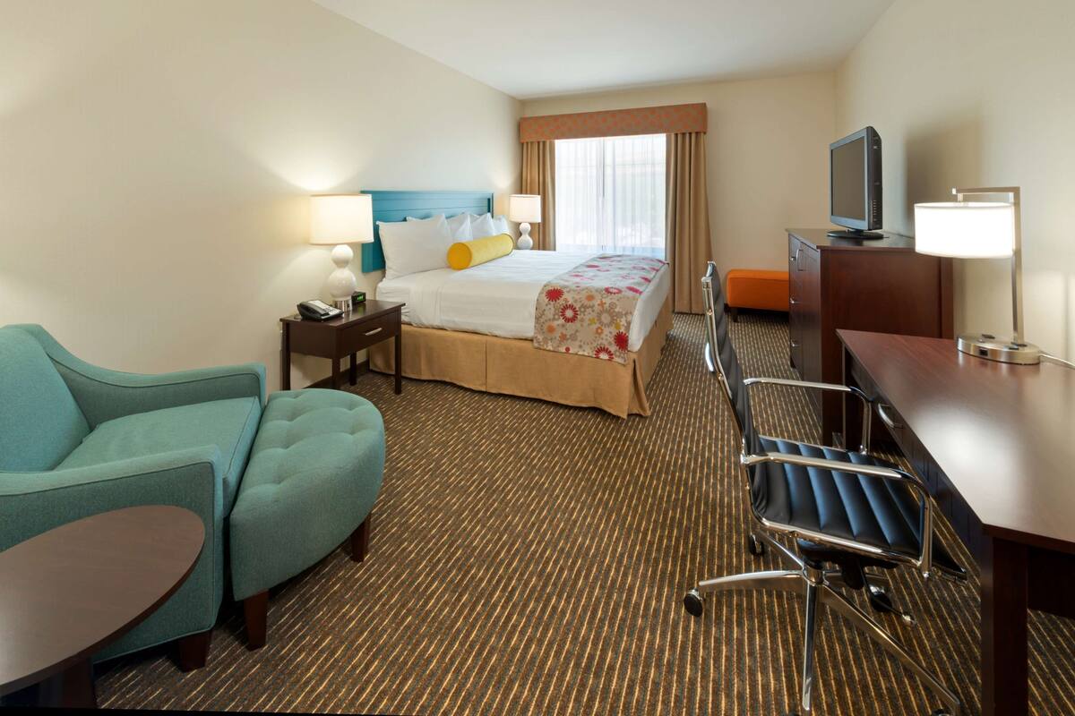 Une chambre d’hôtel équipée d’un lit, d’un bureau, d’une chaise, d’un canapé et d’une télévision.