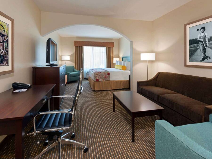 A hotel room with a bed, a desk, a chair, a sofa, and a TV.