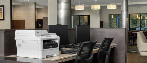 A modern office space with cubicles, a printer, and pendant lighting.