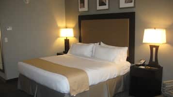 A hotel room with a large bed, two bedside tables with lamps, and three framed pictures on the wall.
