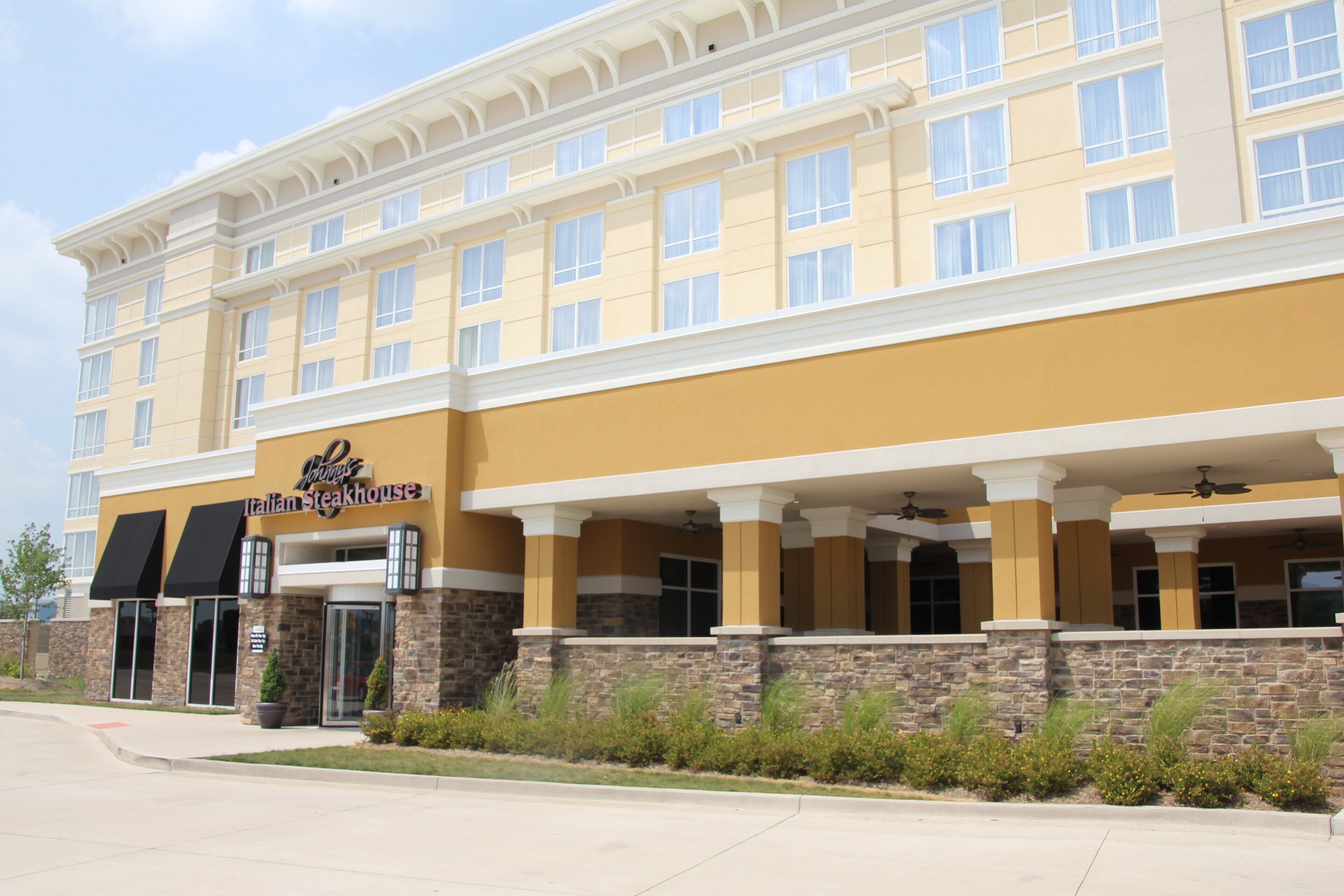 A hotel with a yellow facade, multiple windows, and a sign for 'Johnny's Italian Steakhouse.'