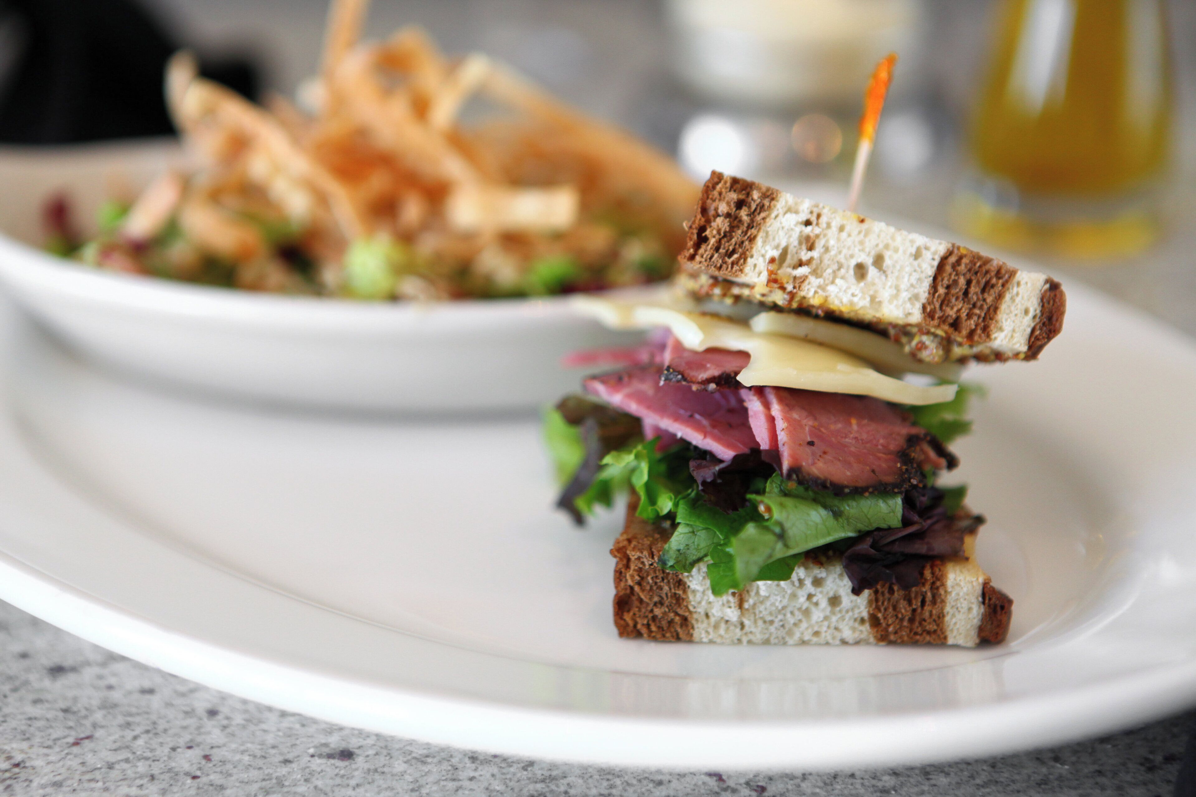 A sandwich with multiple layers of ingredients on a white plate.