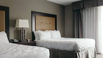 Habitación de hotel con dos camas, una mesita de noche con lámpara, teléfono y cabecero.