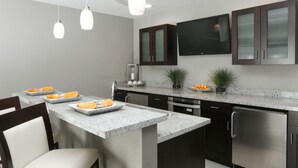 A modern kitchen with a granite countertop, stainless steel appliances, and dark wooden cabinets. - Holiday Inn Hotel & Suites East Peoria by IHG (East Peoria)