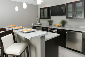 A modern kitchen with a granite countertop, stainless steel appliances, and dark wooden cabinets. - Holiday Inn Hotel & Suites East Peoria by IHG (East Peoria)