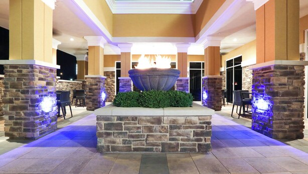 A stone fountain with a fire feature, surrounded by stone pillars and a tiled floor, in a well-lit indoor area. - Holiday Inn Hotel & Suites East Peoria by IHG (East Peoria)