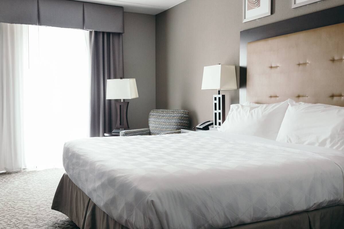 Une chambre d’hôtel avec un grand lit, une chaise, un bureau et une lampe.