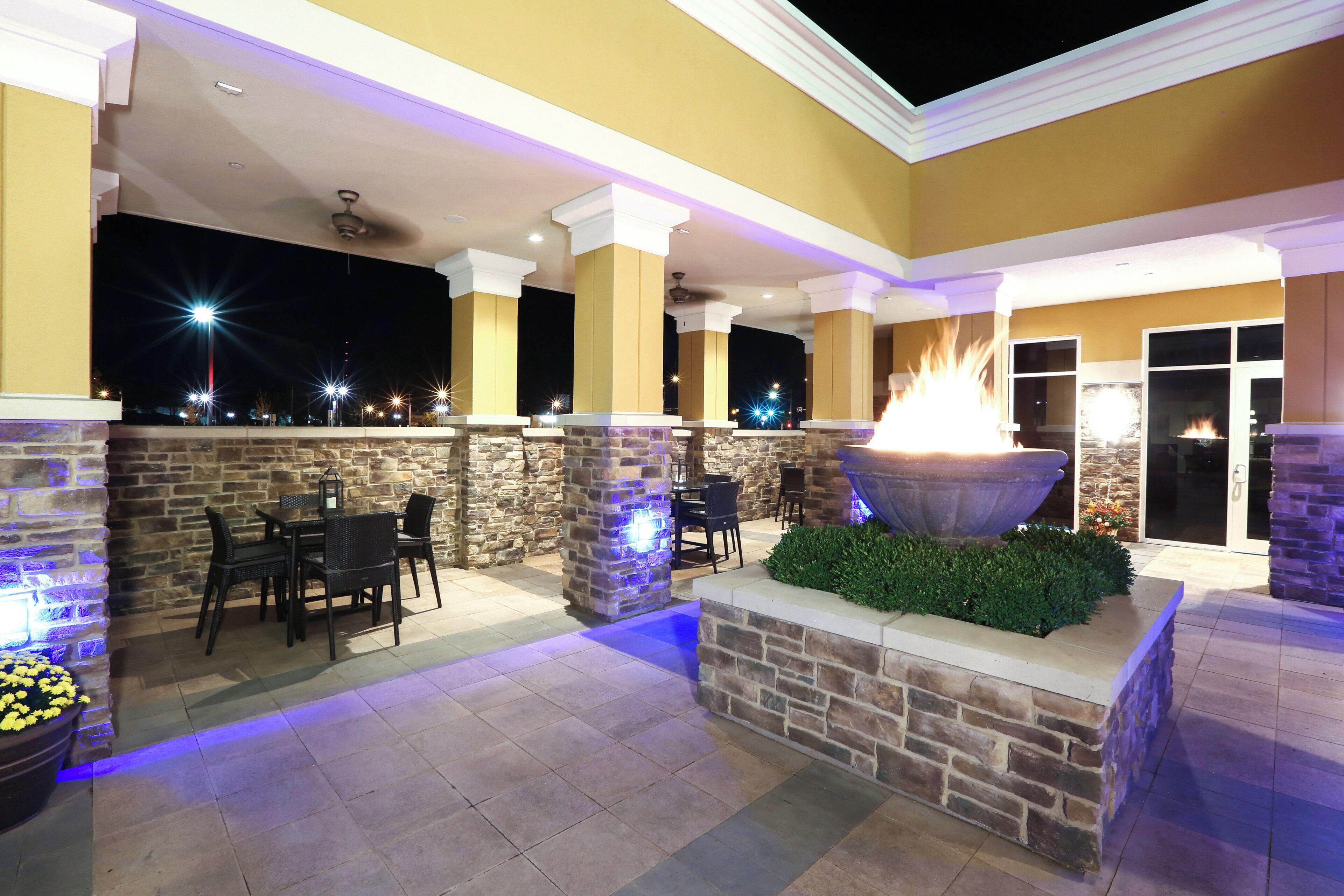 An outdoor patio area with stone walls, a fire feature, and outdoor seating.