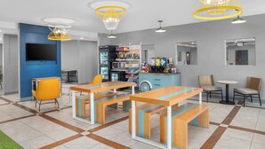 A modern reception area with a counter, seating, and a vending machine. - Spark by Hilton Minot (Minot)