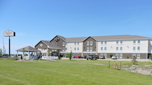 A multi-story hotel with a covered entrance and a parking lot. - Spark by Hilton Minot (Minot)