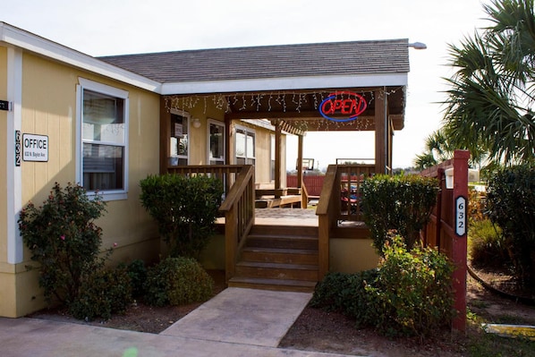 A building with a porch, a staircase, and a sign indicating an office.