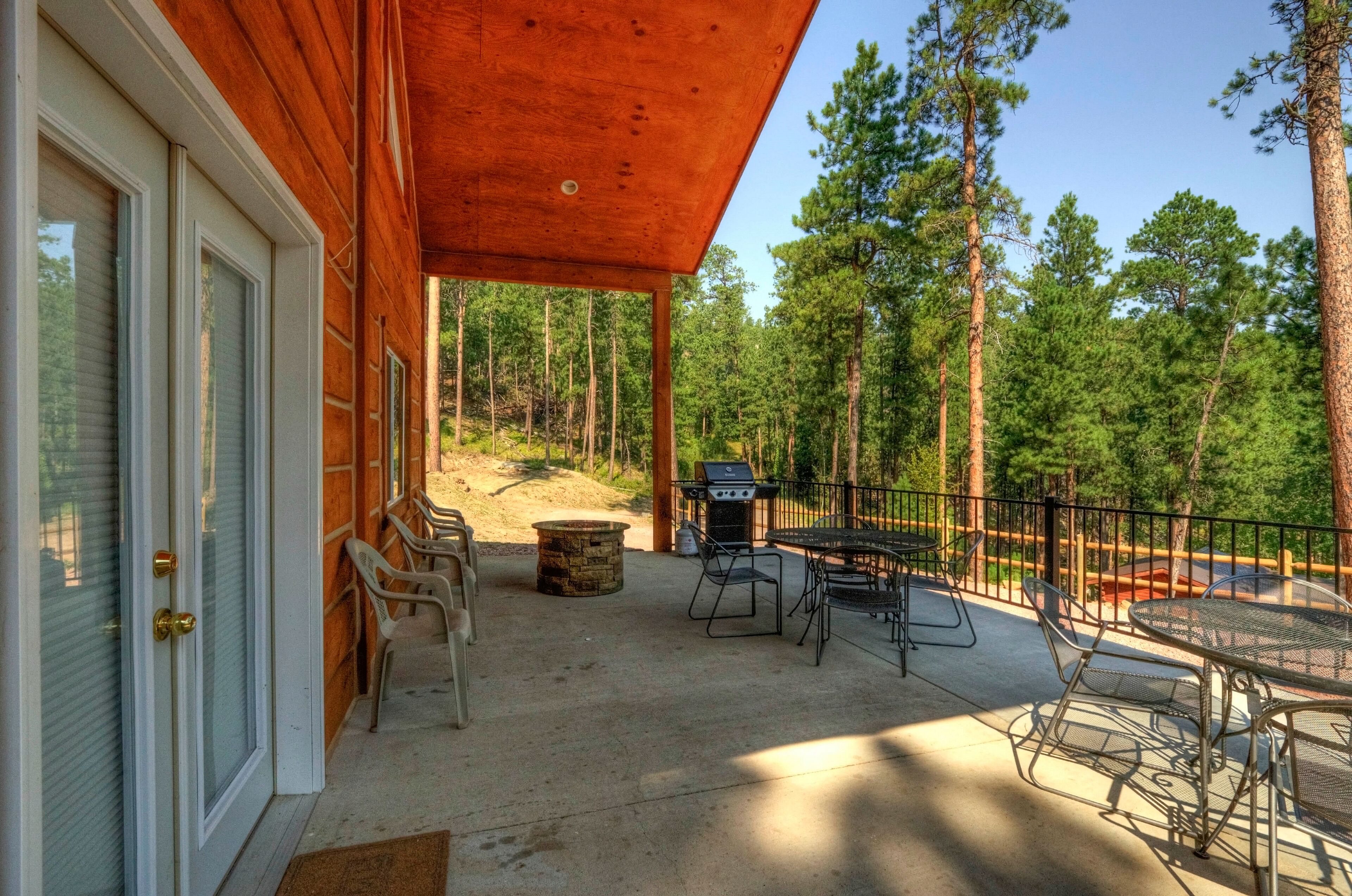 A covered patio with outdoor furniture, a grill, and a stone fire pit.