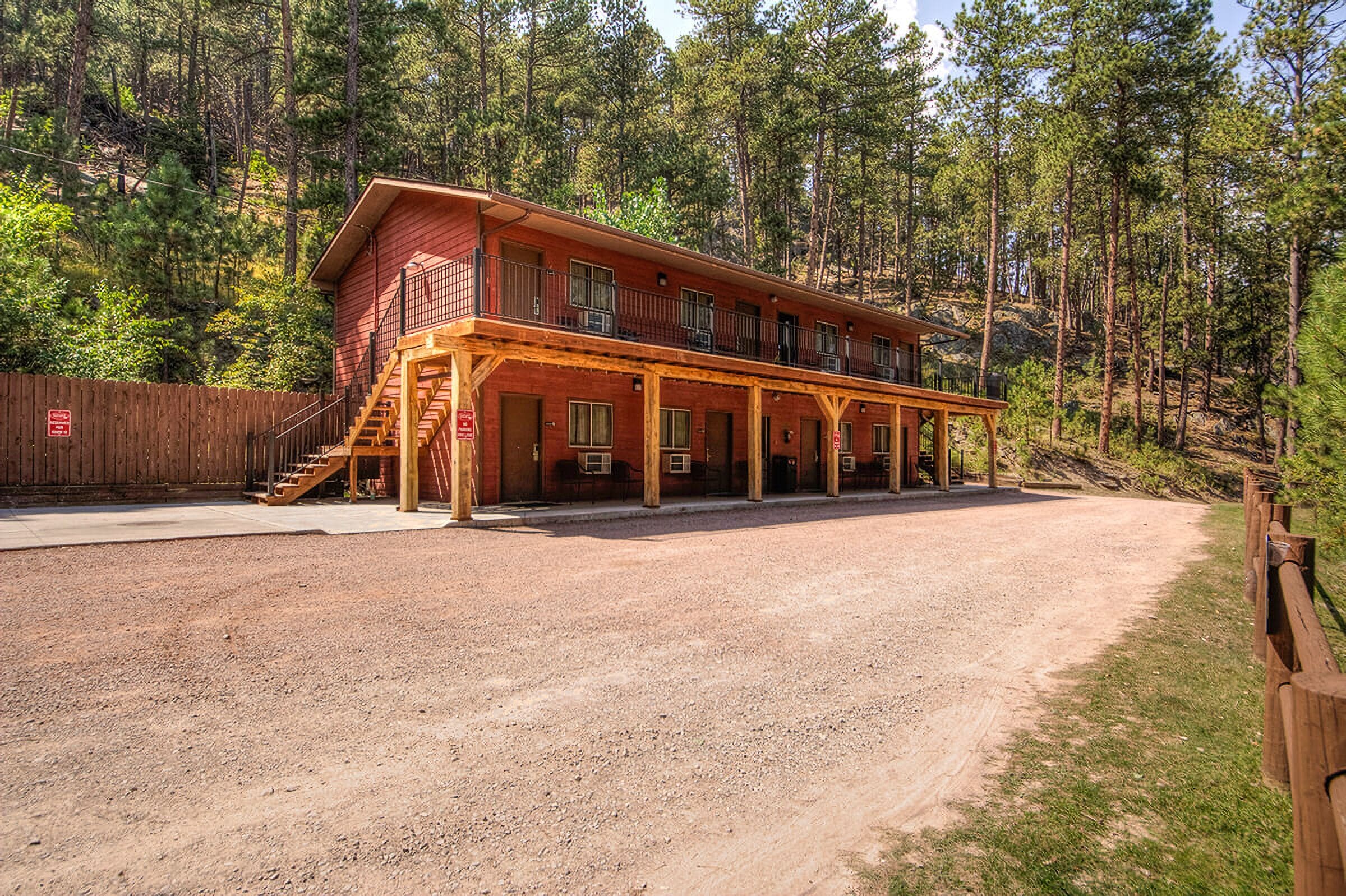 Ein zweistöckiges Gebäude mit einer überdachten Veranda, umgeben von einem Wald.