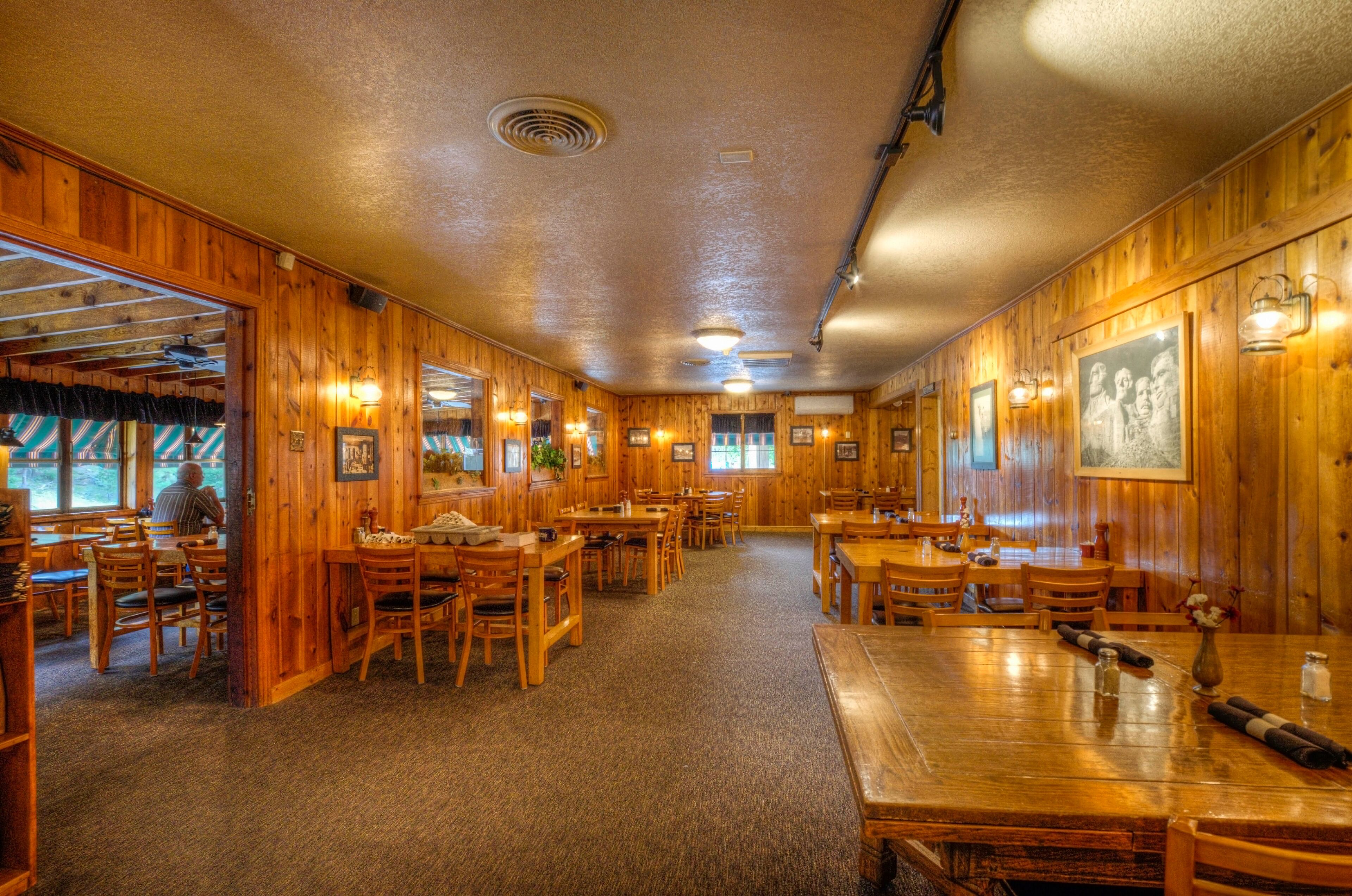 Un restaurante acogedor con paredes y mesas de madera, con fotografías enmarcadas e iluminación cálida.