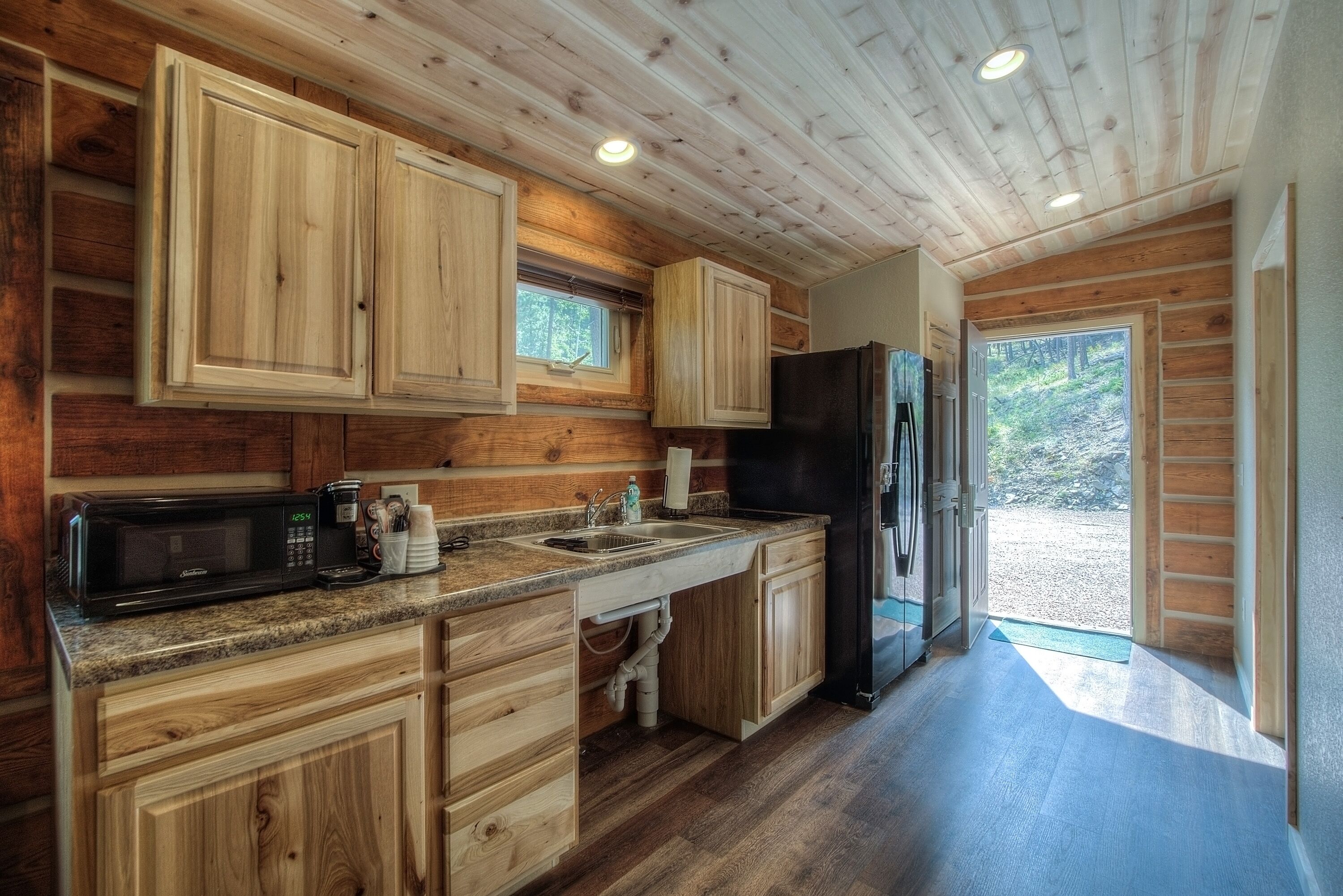 Una cocina estilo cabaña de madera con alacenas empotradas, microondas, lavaplatos y refrigerador.