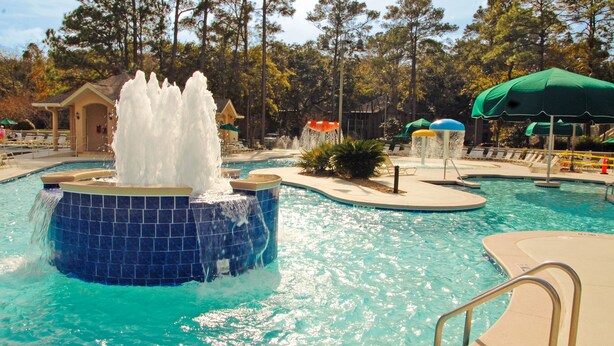A swimming pool with a central water feature and surrounding lounge areas.
