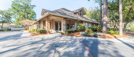 A two-story building with a pitched roof, a covered front porch, and a landscaped front yard with trees and shrubs.