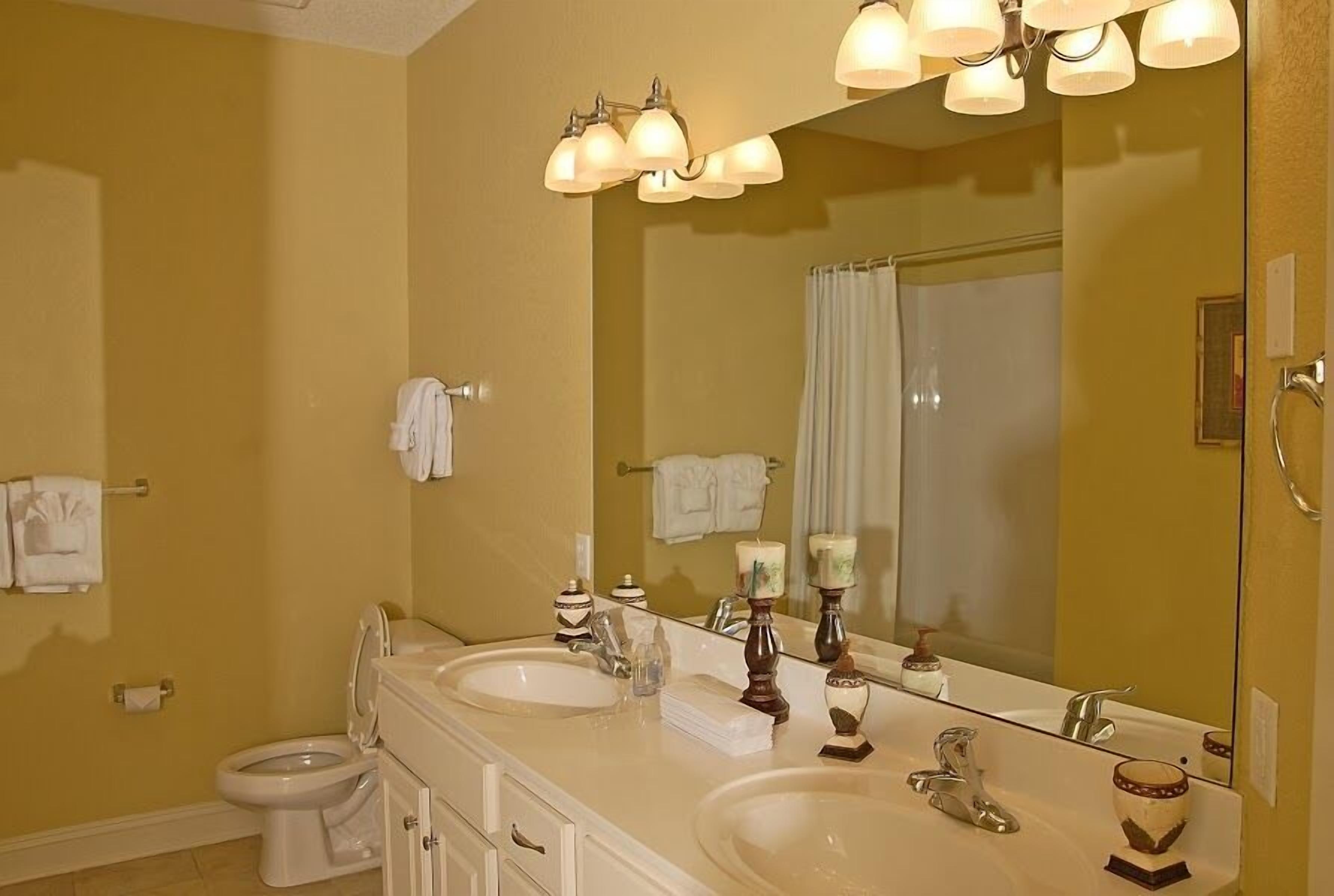 A bathroom with two sinks, a toilet, and a large mirror.