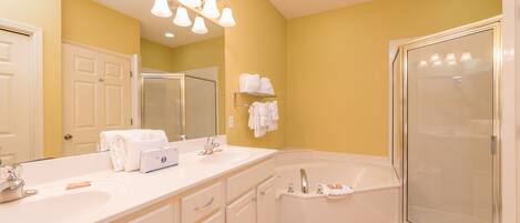 A bathroom with a large mirror, a double sink vanity, a bathtub, and a glass-enclosed shower.