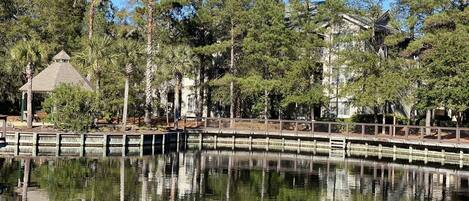Un coin de paradis au bord du lac, avec un belvédère, une jetée en bois et des arbres tout autour.