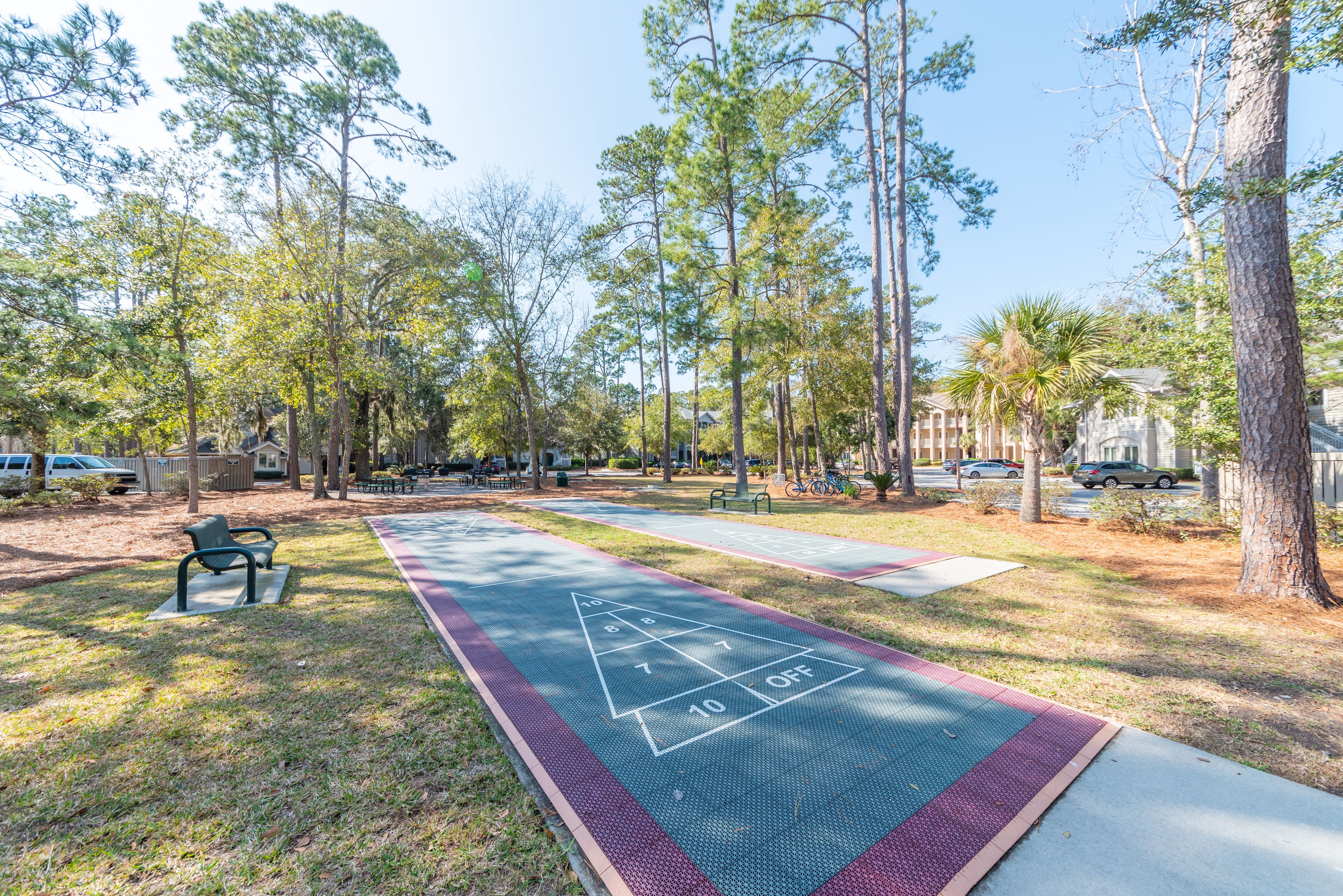 Un parque con una cancha de juego de hojalata, bancos y árboles.