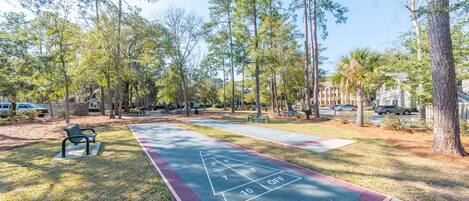 Un parque con una cancha de juego de hojalata, bancos y árboles.