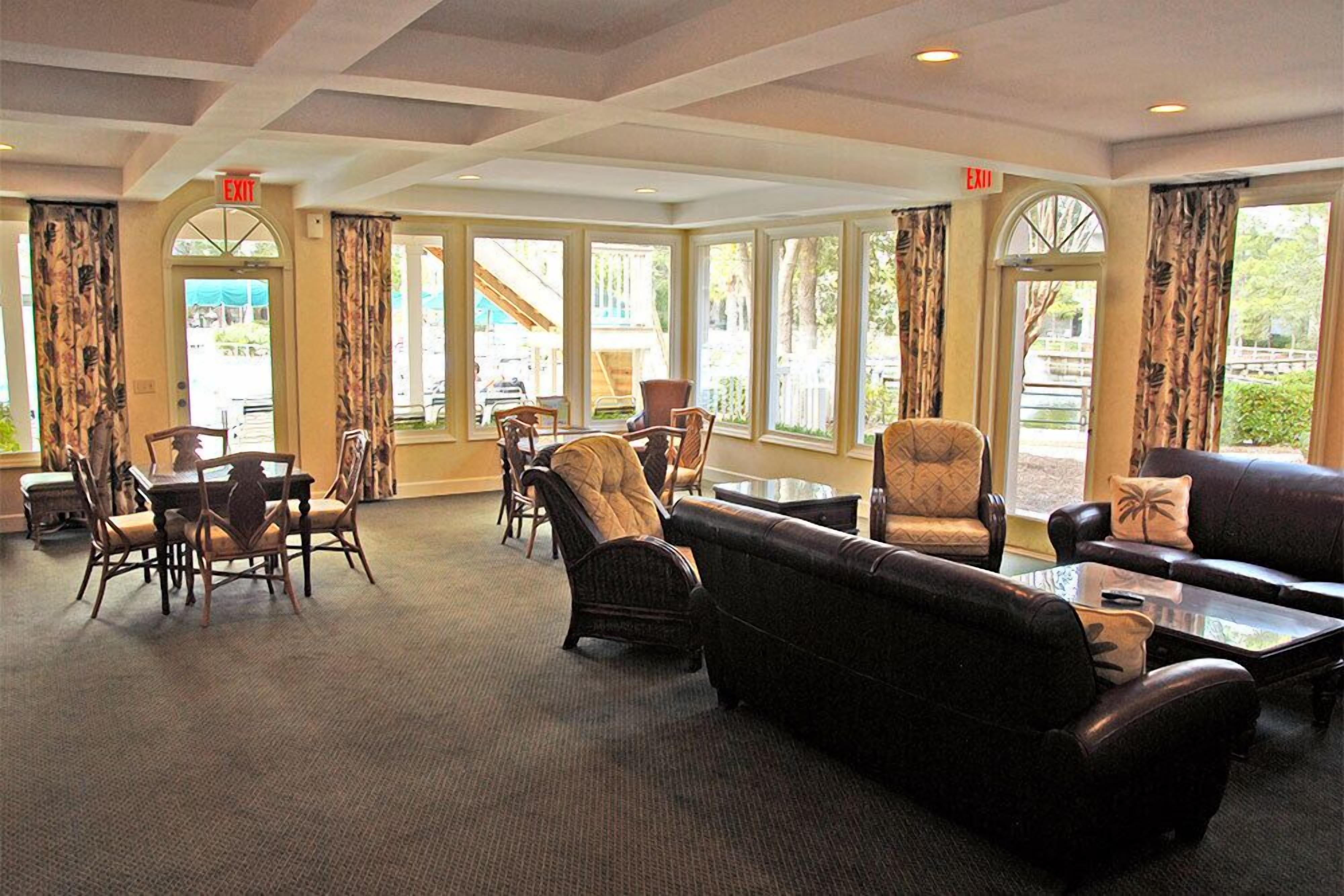 A spacious lobby with a dining area, comfortable seating, and large windows offering views of the outdoors.