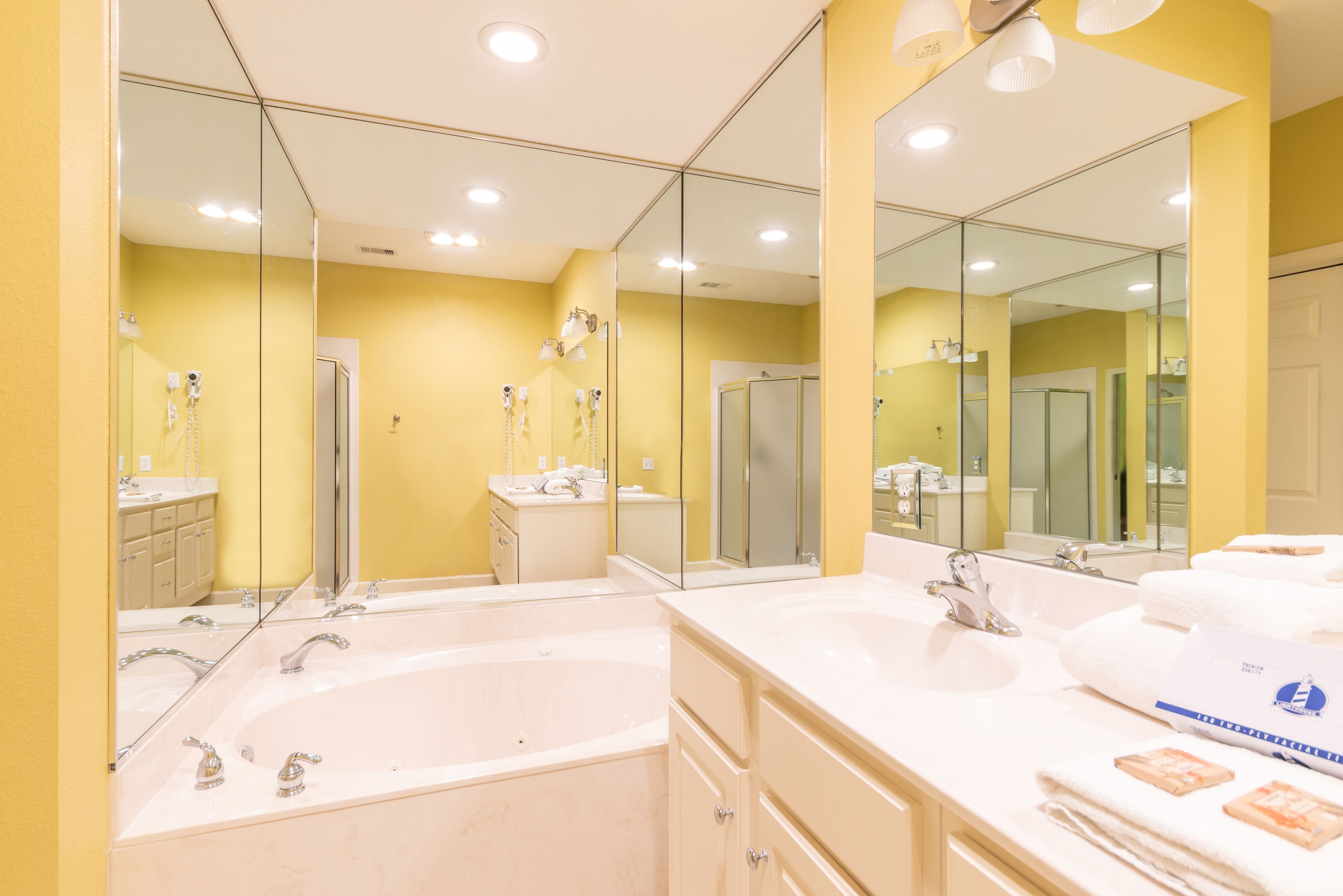 Une salle de bain moderne avec un grand miroir, deux lavabos et une baignoire.
