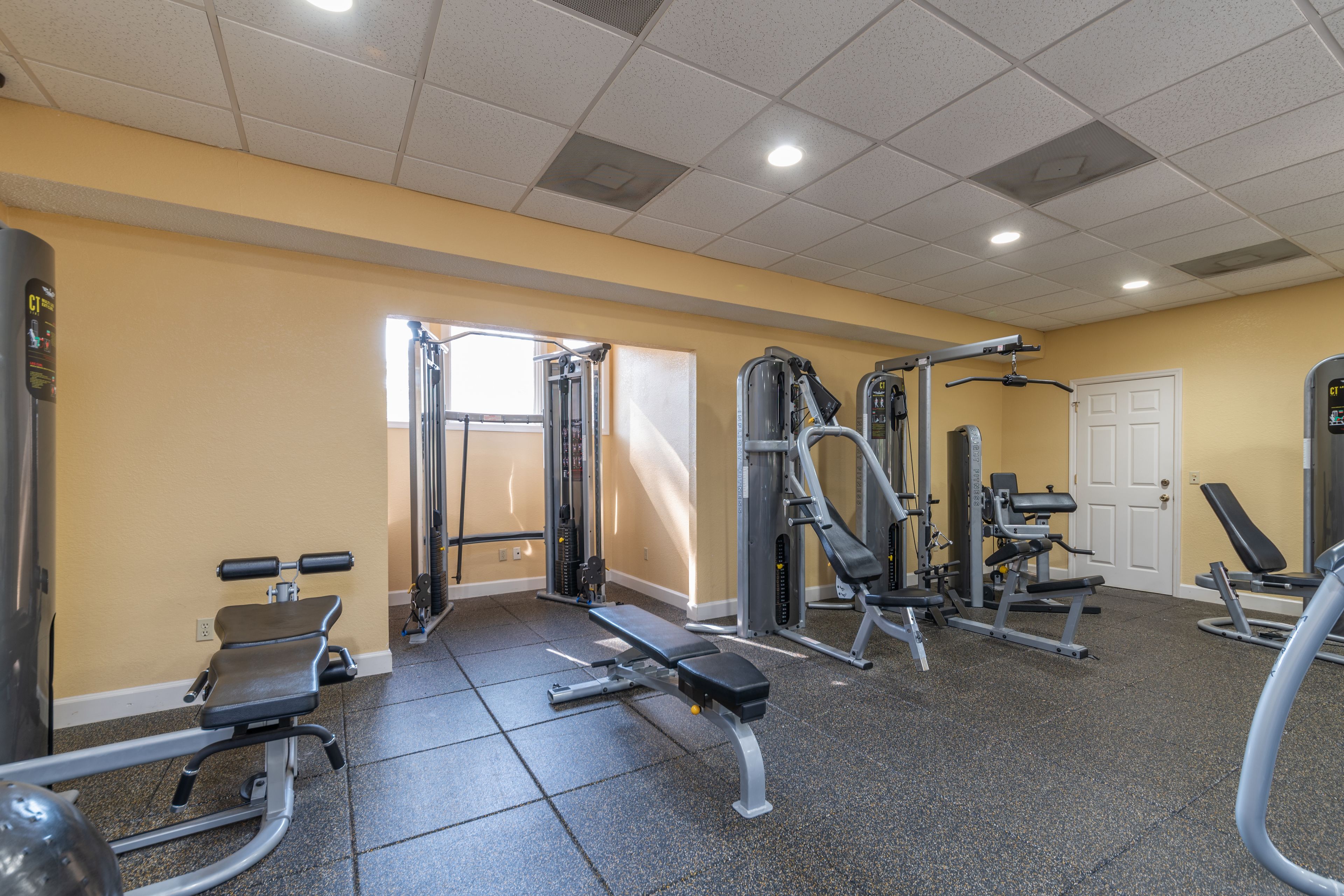 A gym with various exercise machines, a bench, and a door.