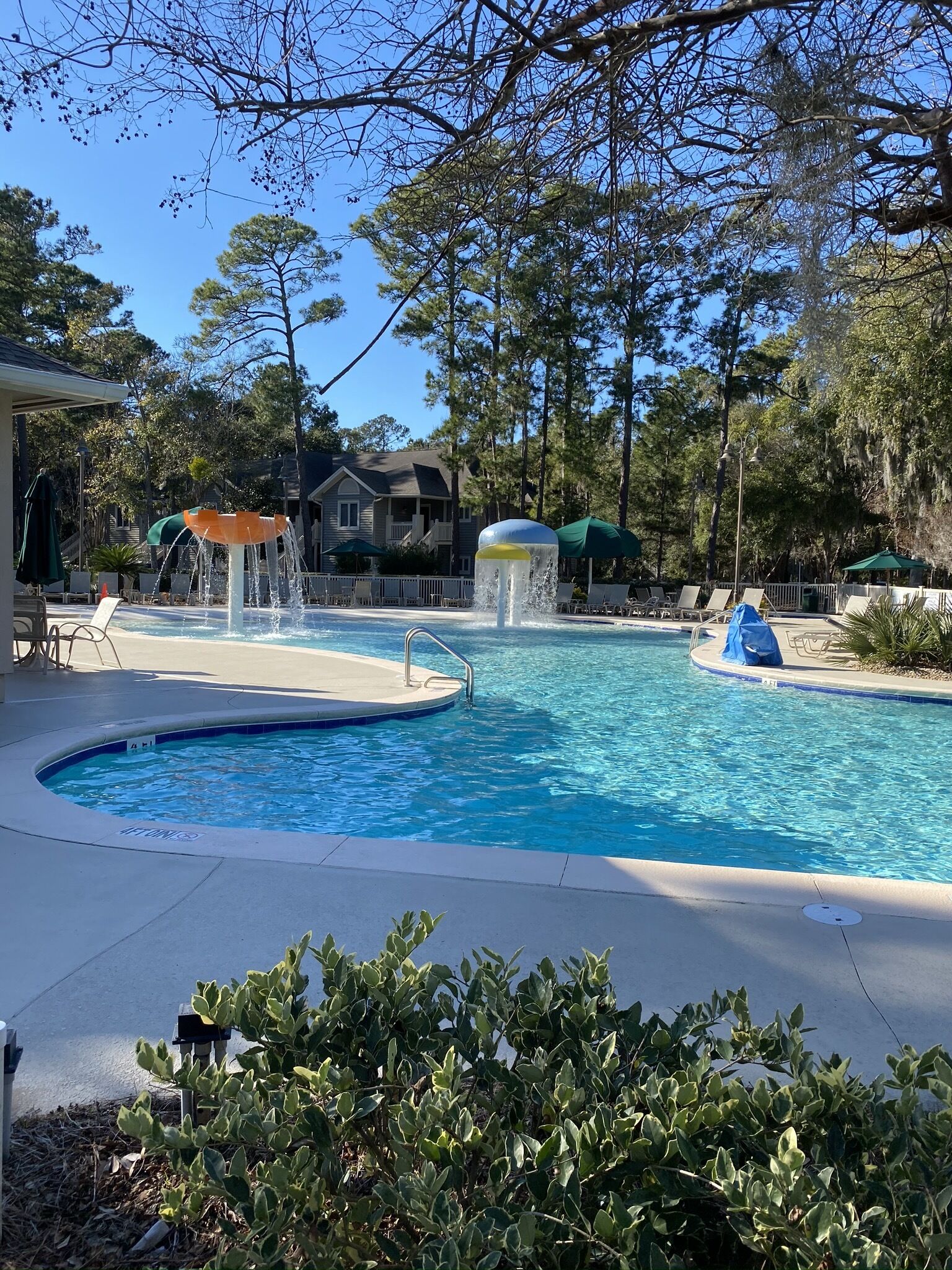 A swimming pool with a water feature, lounge chairs, and a covered seating area.