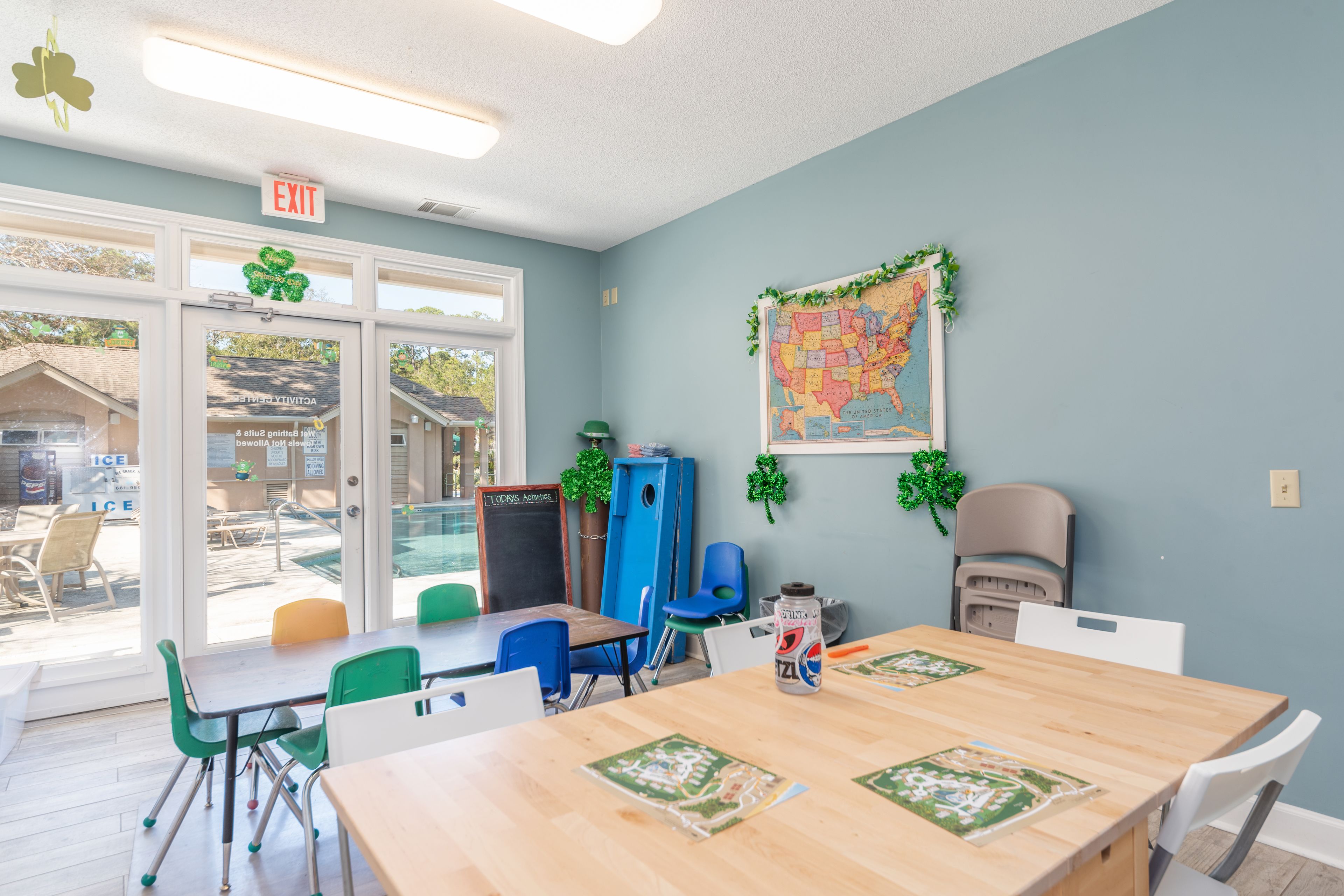 A room with a large window, a map on the wall, and a table with chairs.