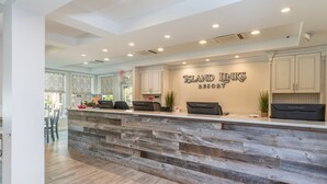 A reception desk with a rustic wooden design, a sign reading "Island Links Resort," and a view of the outdoor area.