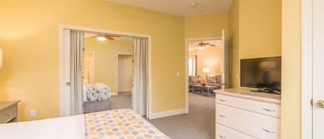 A hotel room with a bed, a dresser, a television, and a ceiling fan.