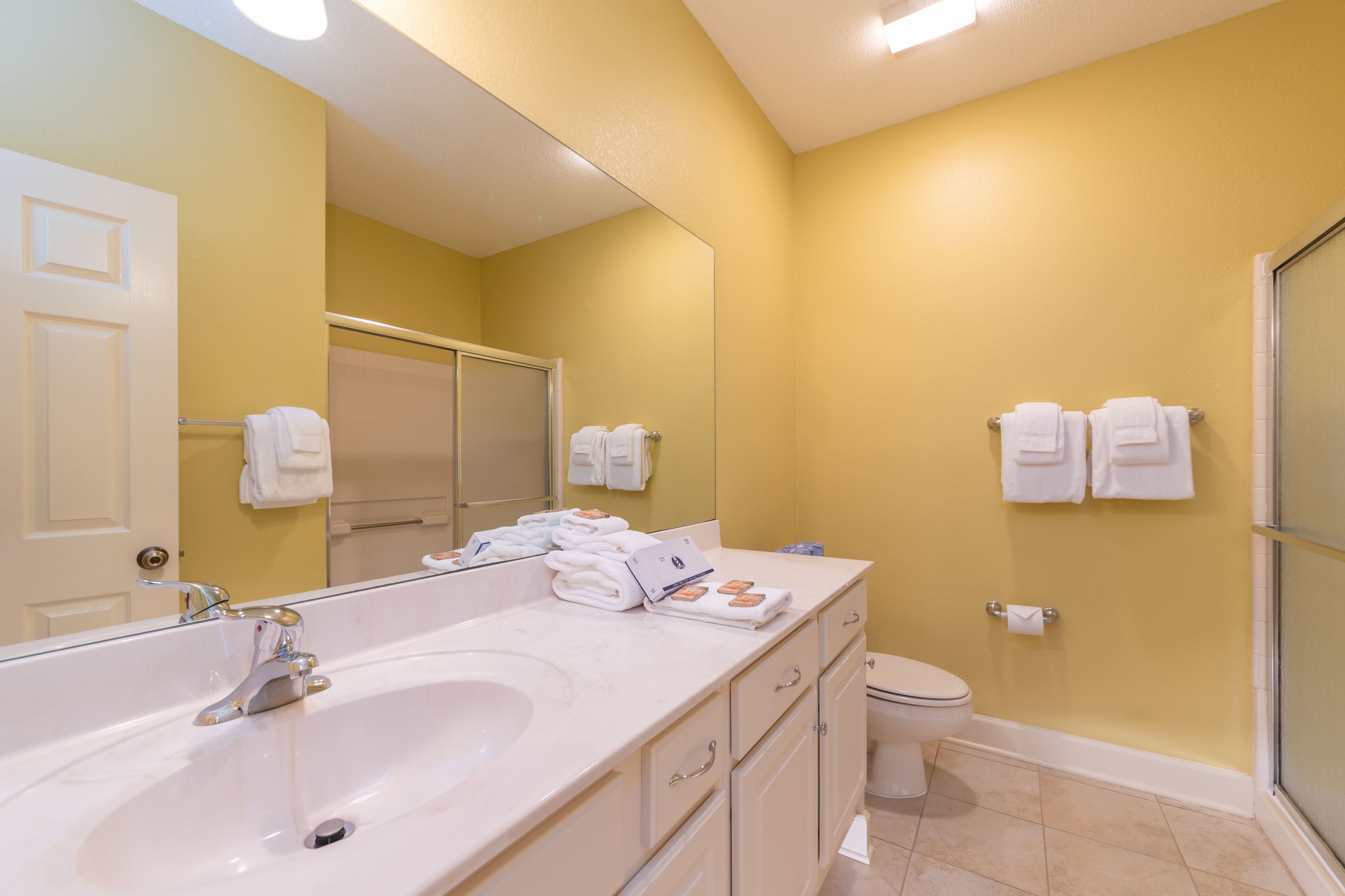 A bathroom with a large sink, a toilet, and a shower. There are towels hanging on the wall and a mirror above the sink.
