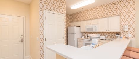 Una cocina con armarios blancos, una encimera blanca y un microondas.